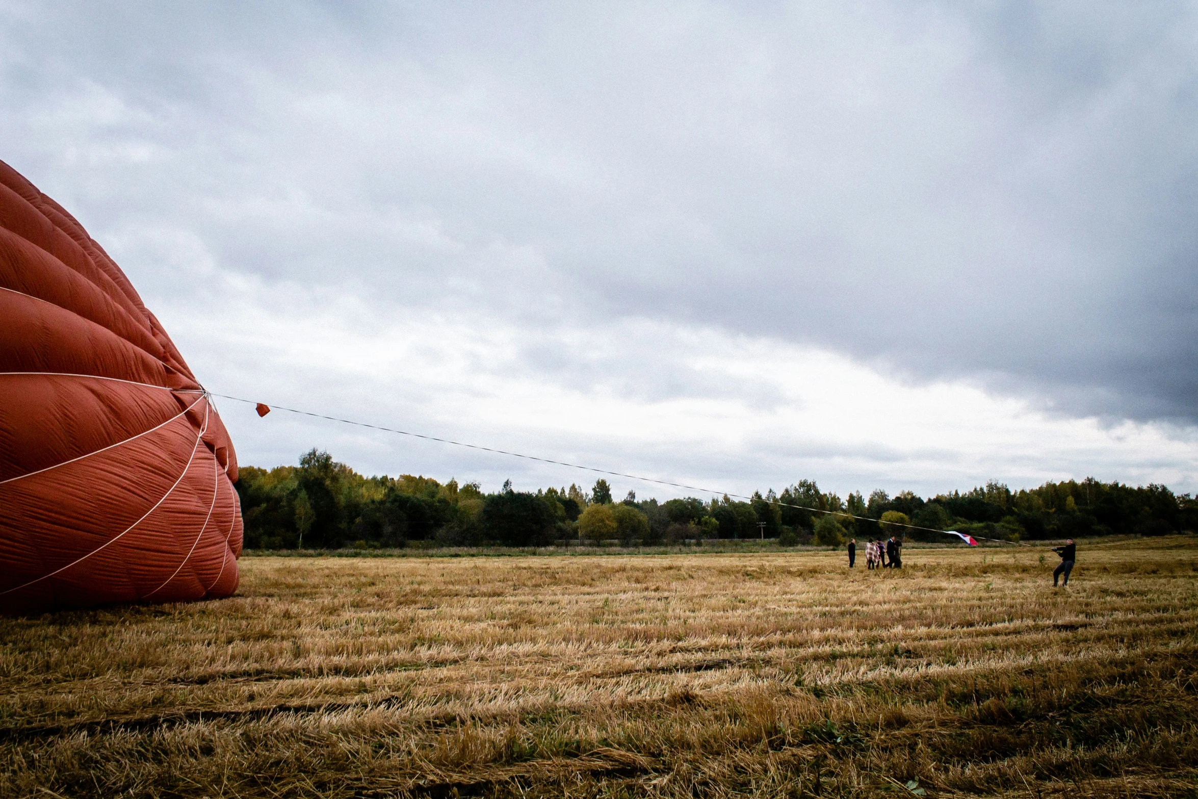 two people standing in a field flying a large balloon