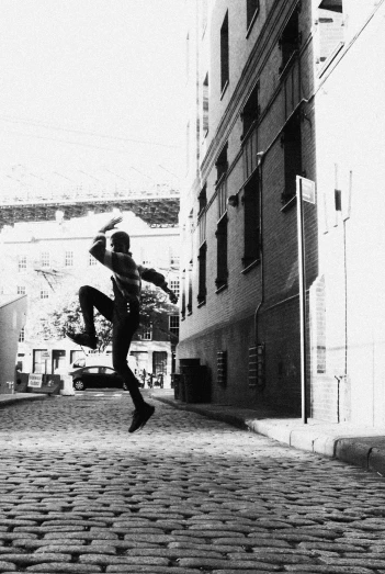 a boy jumps on a cobblestone sidewalk in a black and white po