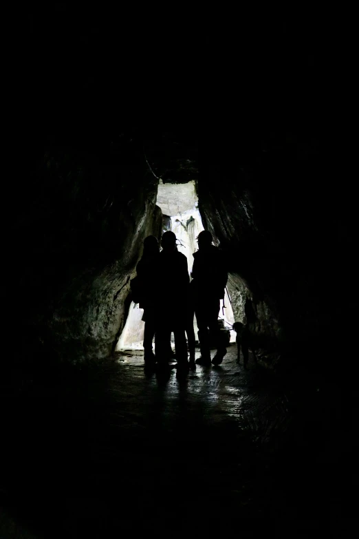 five people walk through a dark cave door
