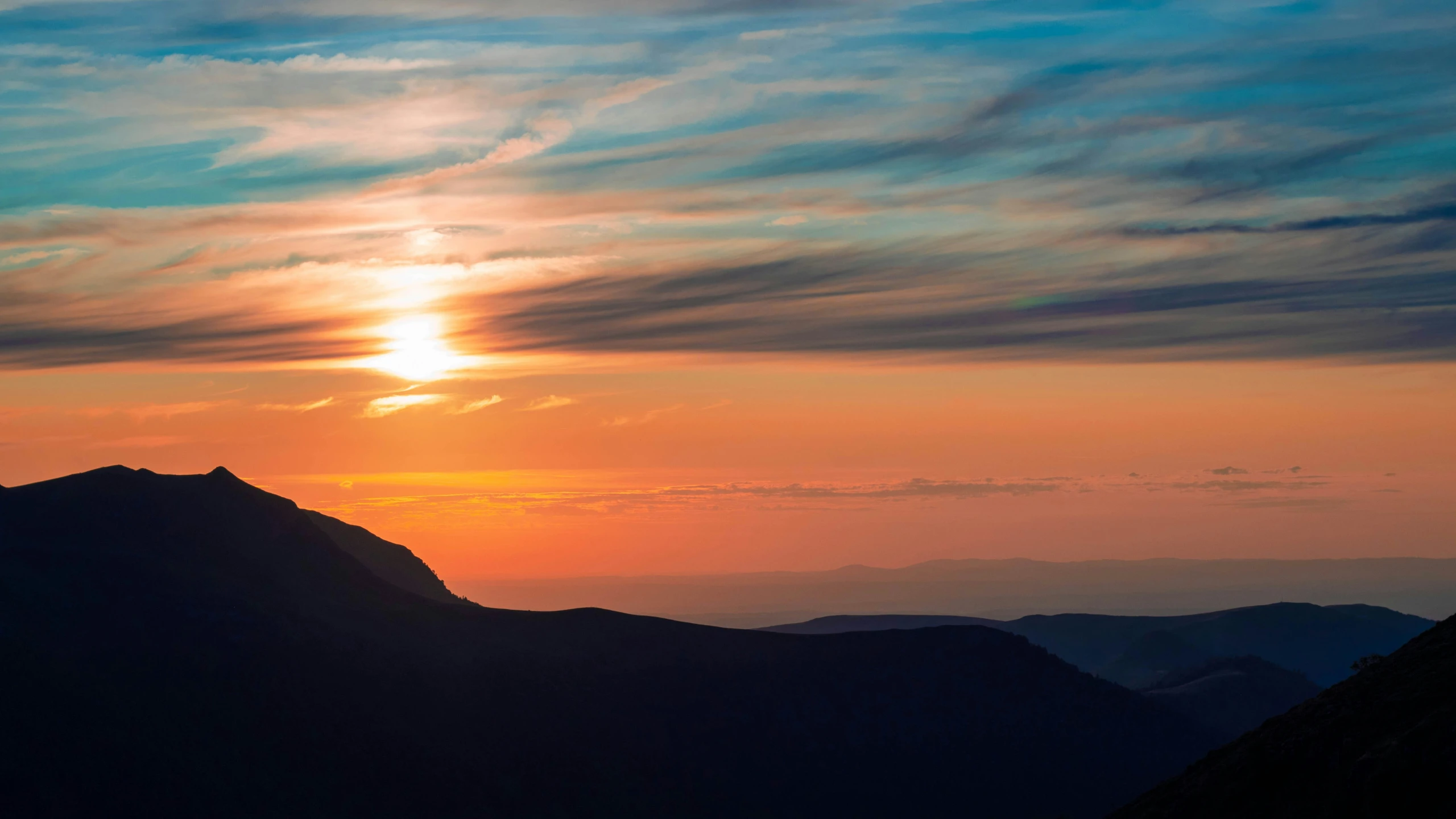 the sun setting behind the peak of a mountain