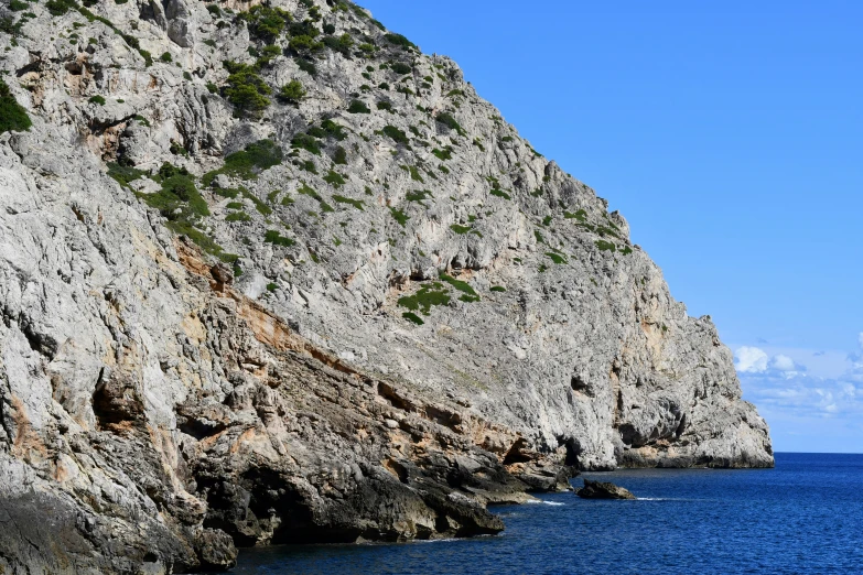 rocks with vegetation are seen from a boat on the ocean