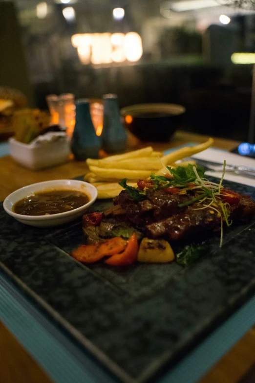 a large piece of steak, fries, and french fries is on a plate