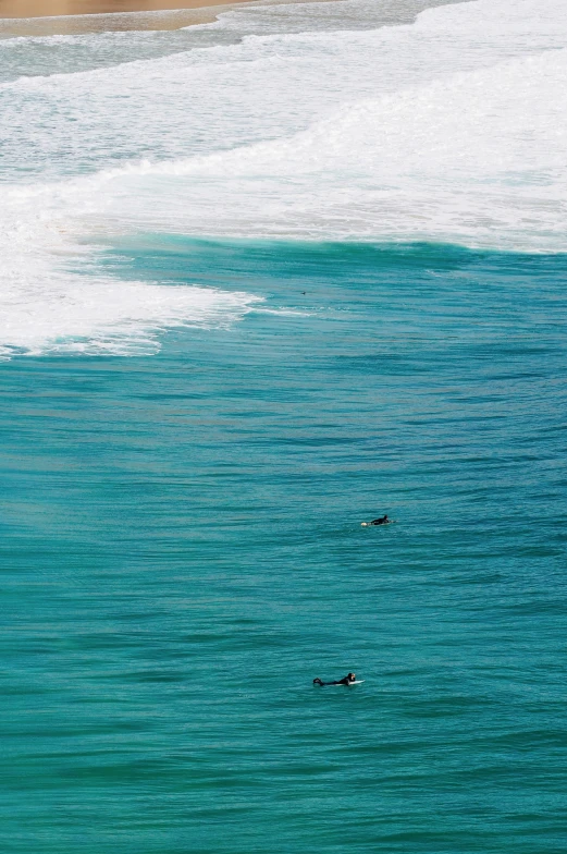 two surfers are riding their surfboards in the blue water