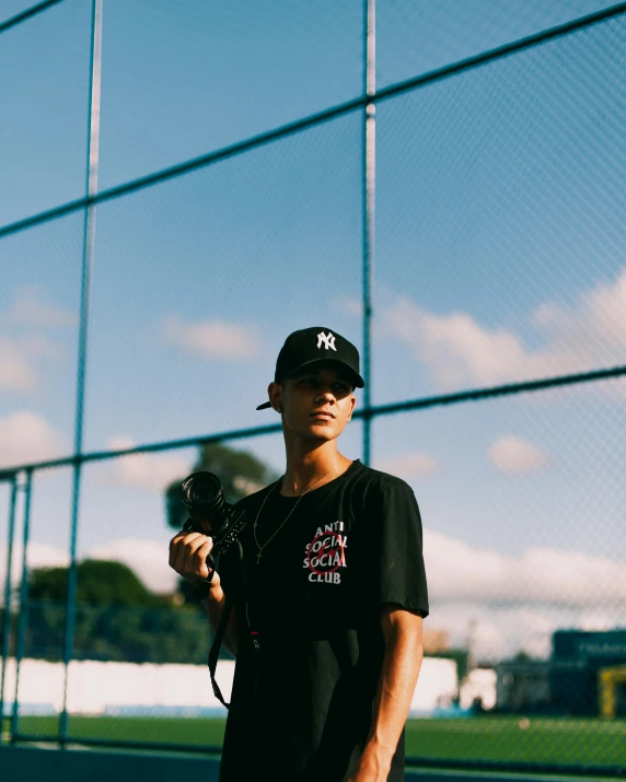 a man wearing a black baseball cap holding up a camera