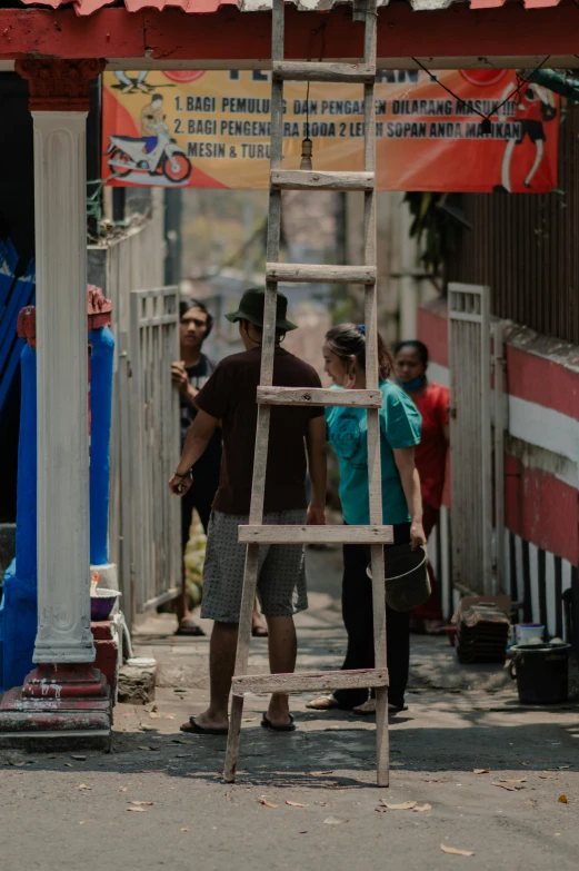 three people standing on the street and climbing up a ladder