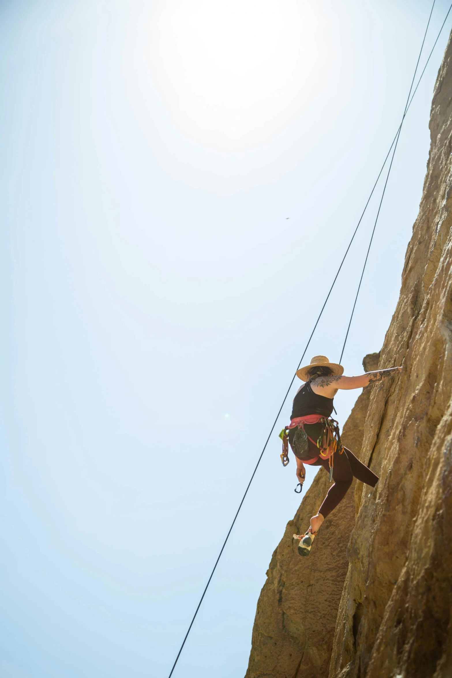 man on climbing rope with hat on standing on the edge of a mountain