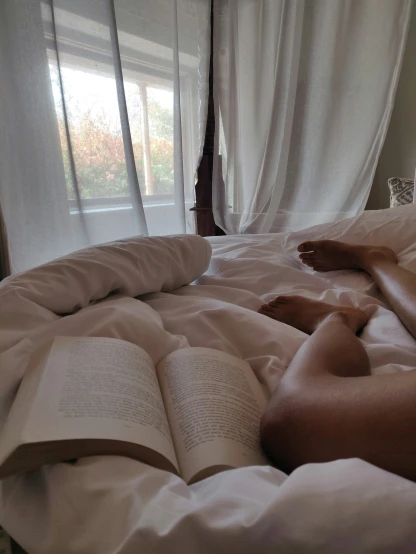 a person laying in bed reading an open book