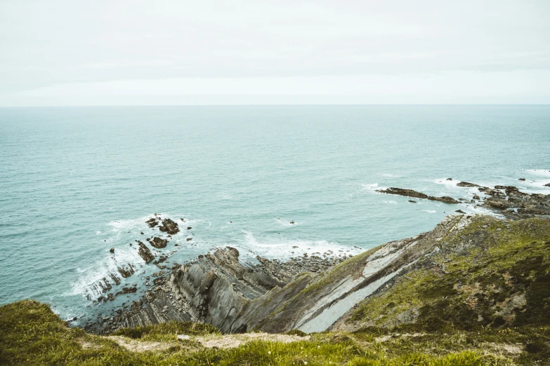 a view of the ocean, rocks and vegetation by the shoreline