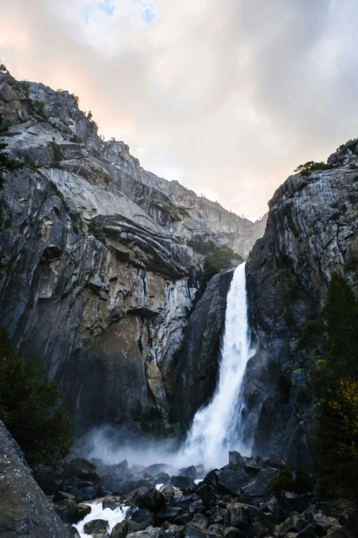 a waterfall cuts into some rocks on a cloudy day