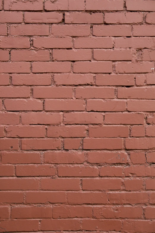 a brick wall with red colored paint and small black spots on it