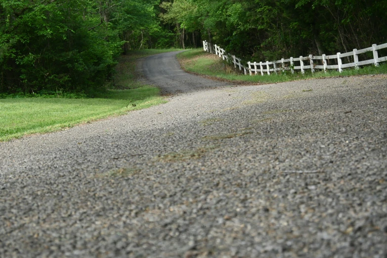 a white fence next to a gravel road in a green field