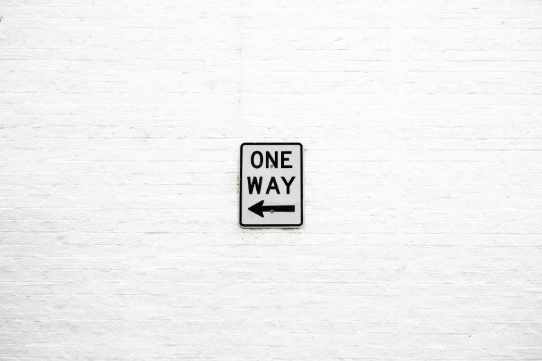one way sign painted on white brick wall