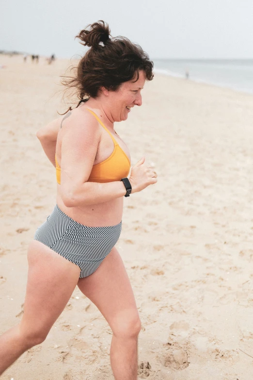 a woman wearing a bikini running on a beach