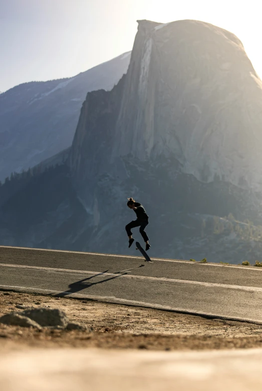 a man skating down a street in front of a mountain