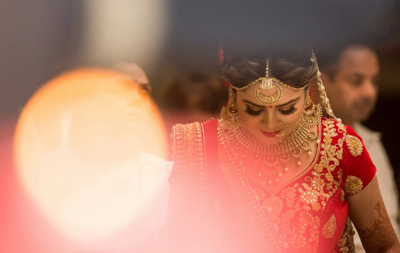 woman in red dress with gold jewelry and an orange lamp