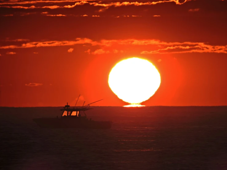 a large fishing boat at sea with the sun setting