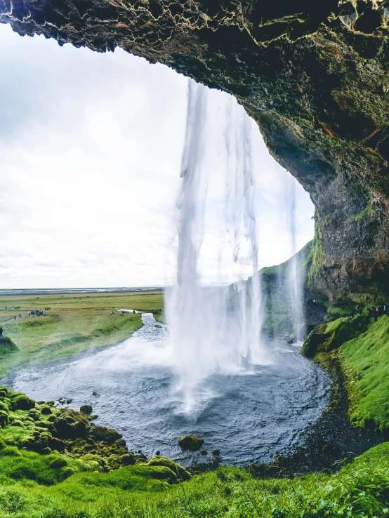 a waterfall sits at the edge of a body of water