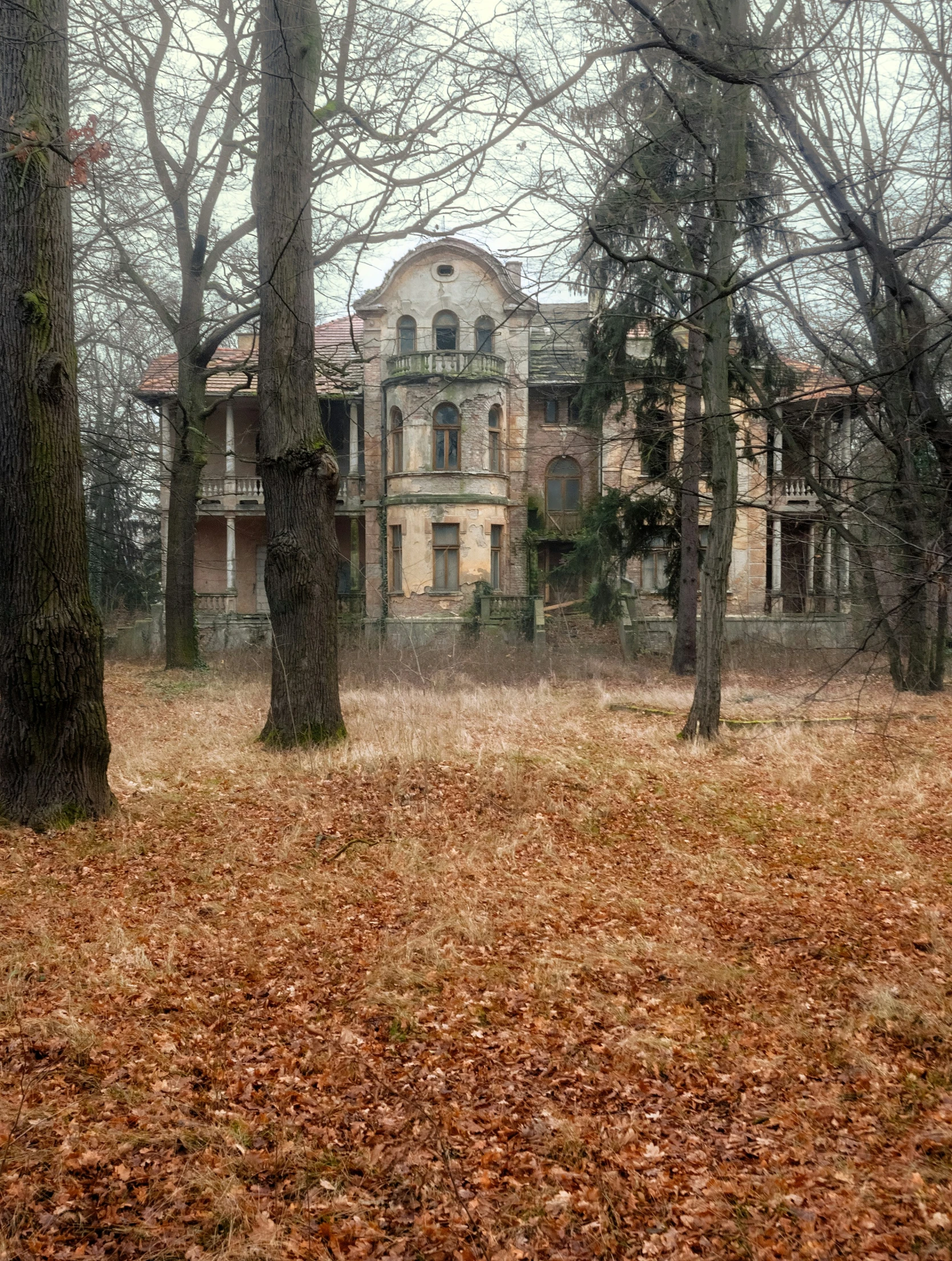an old, abandoned house in autumn with leaves on the ground