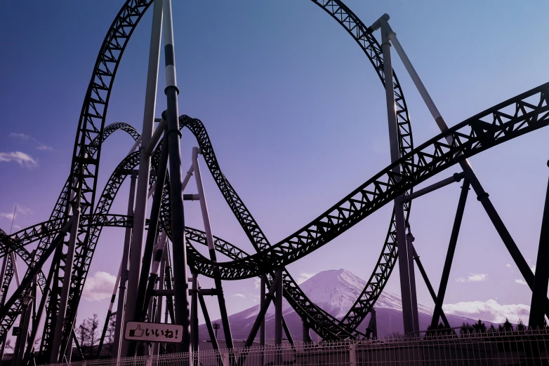 a roller coaster with mountains in the background