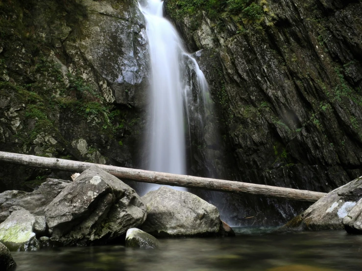 a stream flowing under a huge rock wall