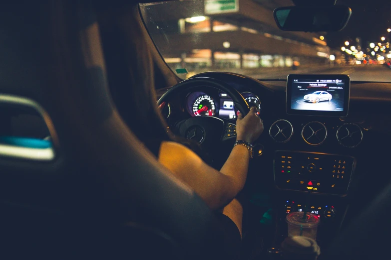 a man driving a car in the dark with his hands on the steering wheel