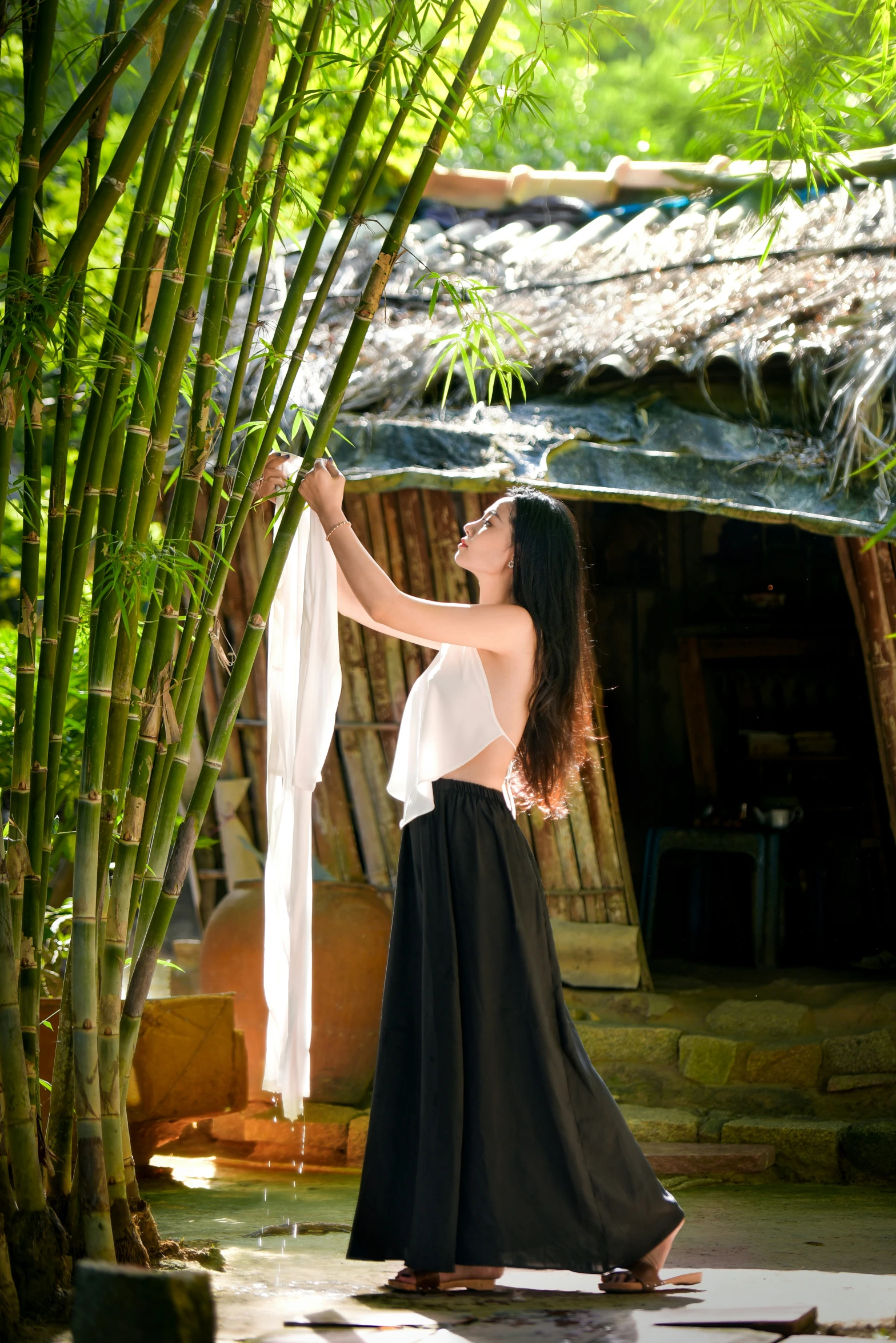 the woman stands next to bamboo plants and has her arms outstretched