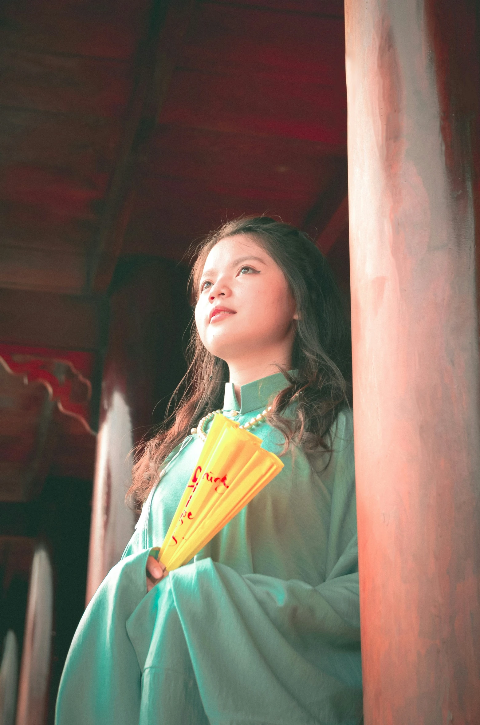 the woman is holding a fan and looking up