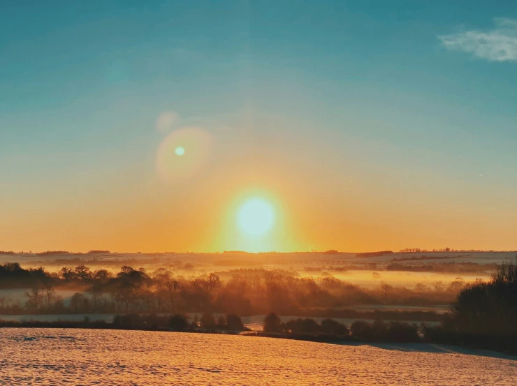 the sun is rising over a snowy plain