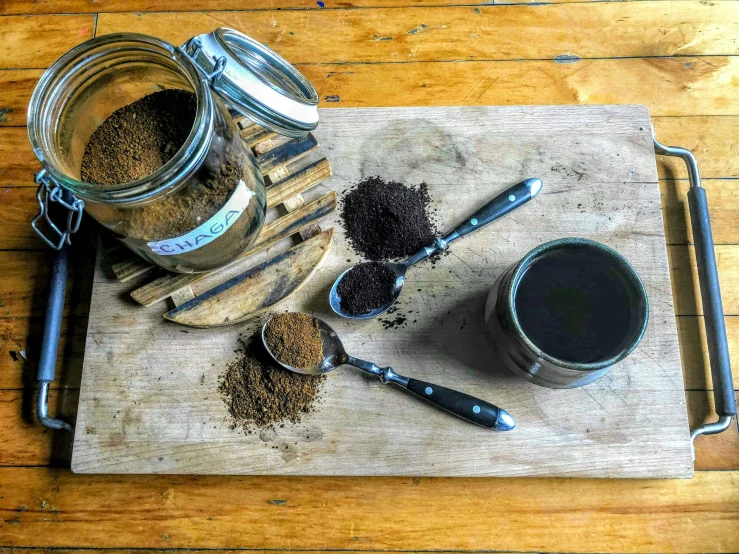 two mason jars with seasonings and spoons on a  board