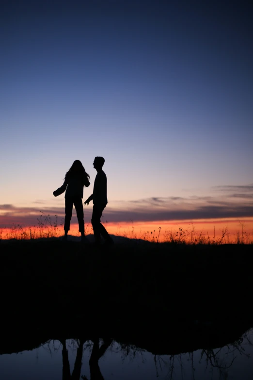 a man and woman holding hands while standing on a hill