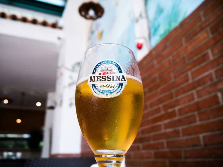 a beer is sitting in a glass in front of a building