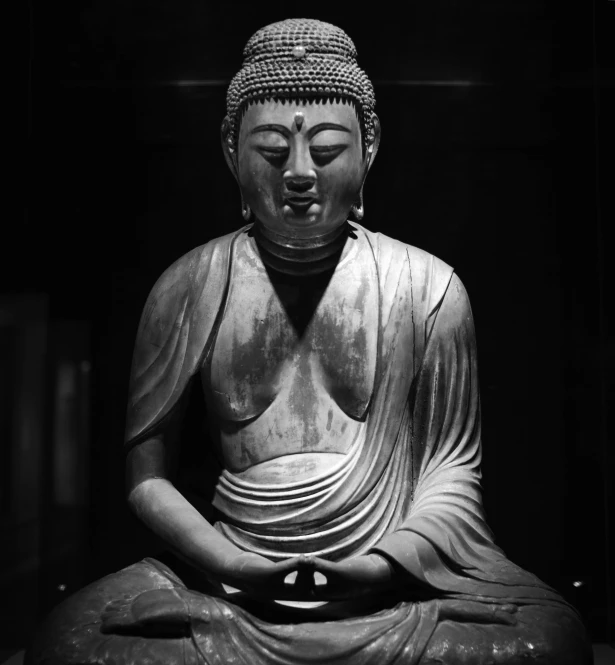 a statue of a seated buddha sitting in a black and white po