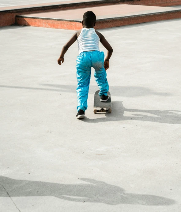 a boy wearing blue pants skateboards in concrete