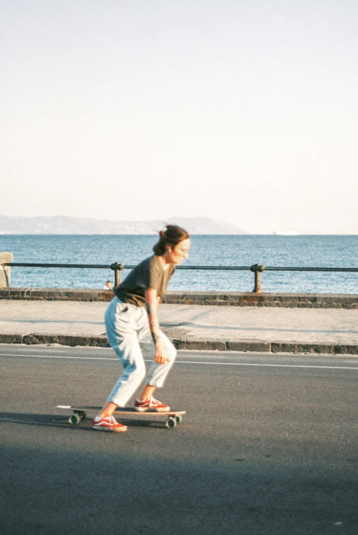 a person riding a skateboard down a street next to the ocean