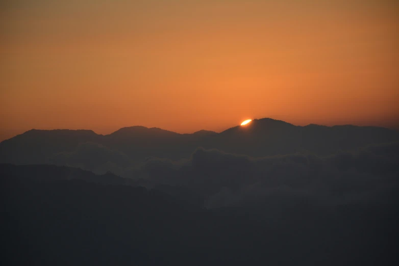 the setting sun behind the mountain ranges in the distance