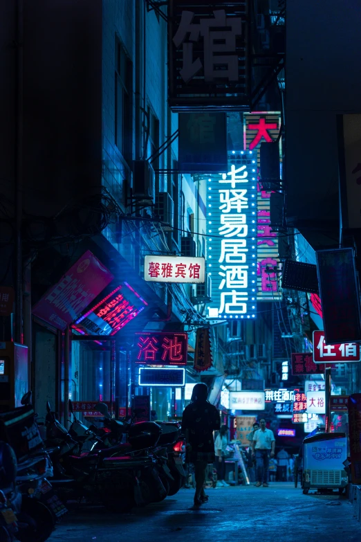 a man on the sidewalk next to building with lit neon signs