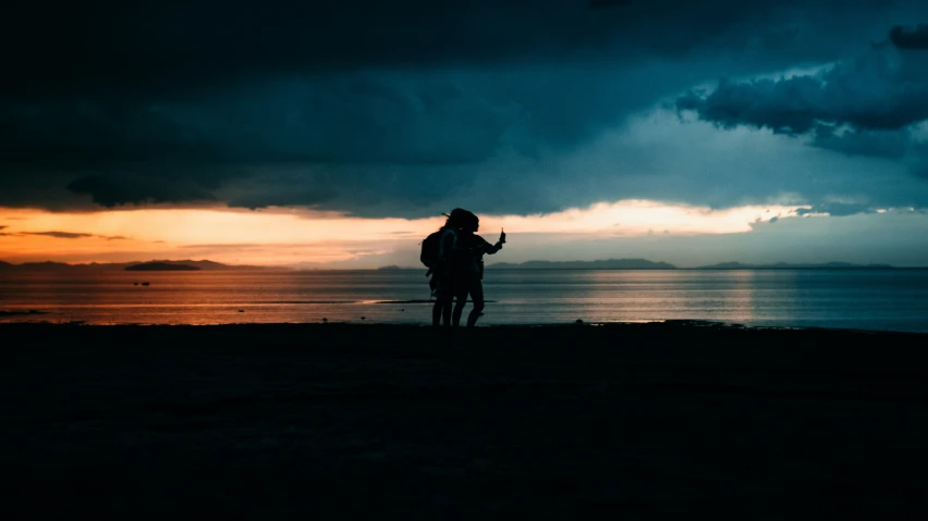 a person standing on a beach with the sun setting behind them