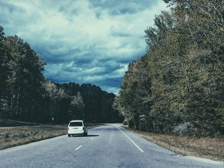 car traveling down the road on a cloudy day