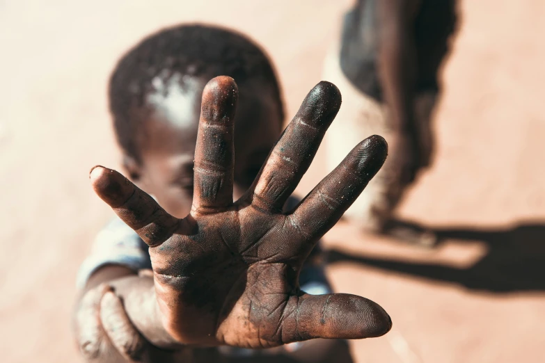 a small child with dirt on his hands showing it