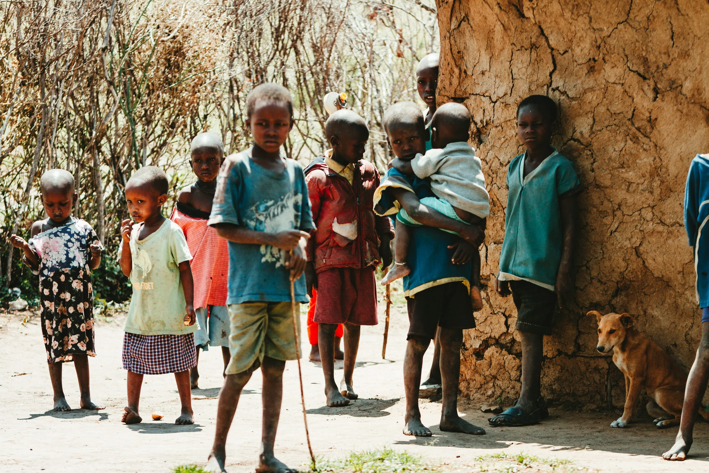 a group of children and a dog standing next to a stone building