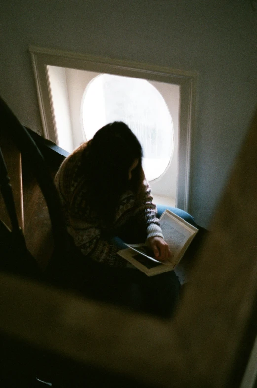 the girl is holding her notebook while sitting on the edge of a window