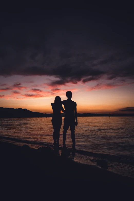 couple standing in front of the ocean at sunset