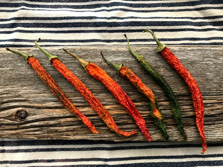 three red peppers on top of a piece of wood