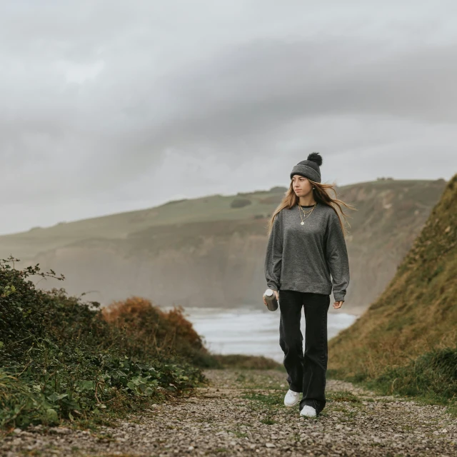 the woman walks down the path of a deserted area near a mountain