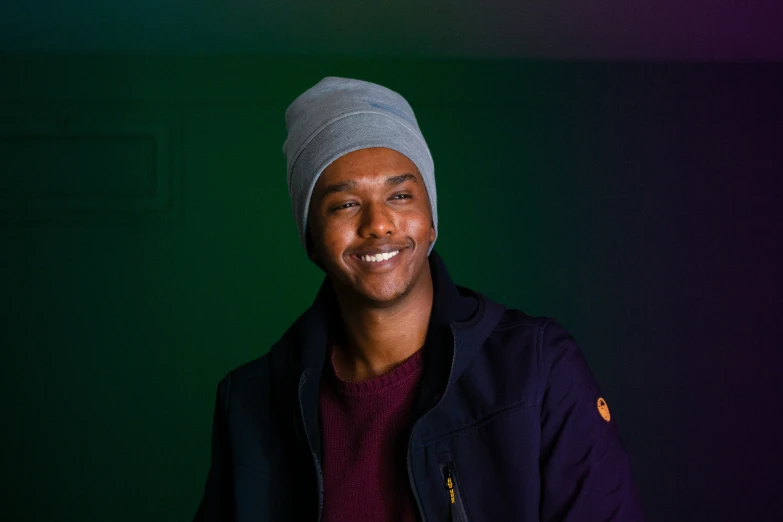 a man wearing a blue coat smiling in a black room