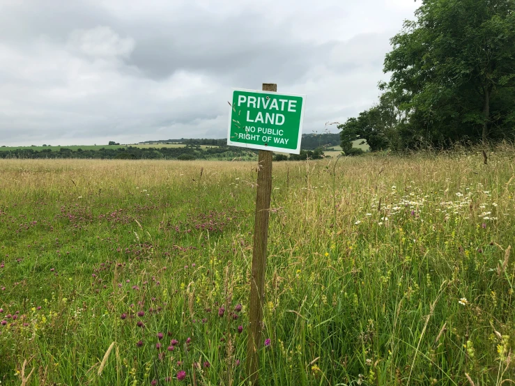 a private land sign in the middle of a grassy field