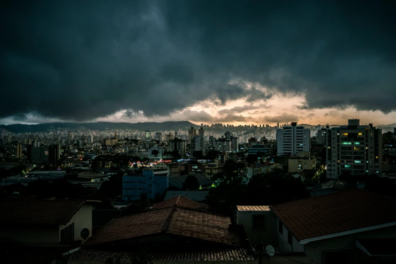 a dark cloud looms over a city as it sun peeks down