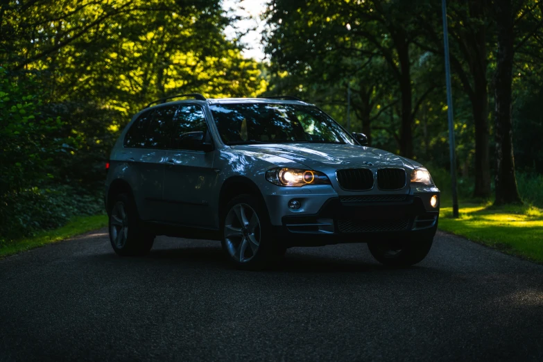 a bmw parked on the side of a tree lined road
