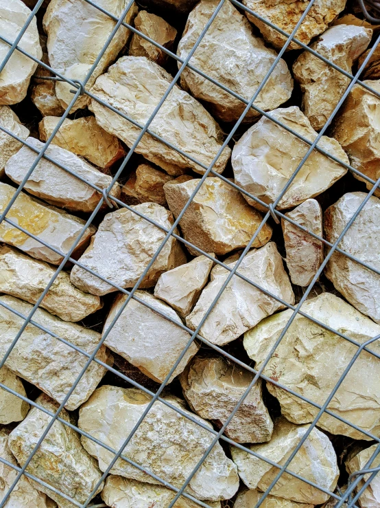 many rocks on the ground behind a metal fence