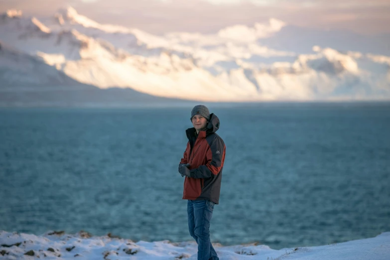 a man standing near the ocean in the snow